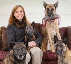 A woman sitting on the couch with her dogs.